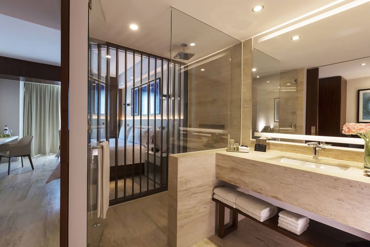 A modern bathroom with a large mirror, a vanity, and a bench.