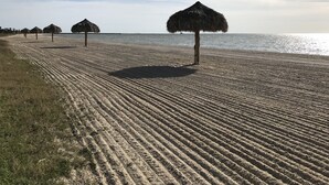 A beach with a thatched-roof hut and a grassy area. -  Copano Bay Sunset - LOCATION! LOCATION! LOCATION!!! (Rockport)