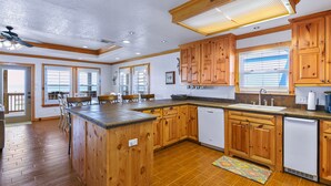 A spacious kitchen with wooden cabinets, a central island, and a dishwasher. -  Copano Bay Sunset - LOCATION! LOCATION! LOCATION!!! (Rockport)