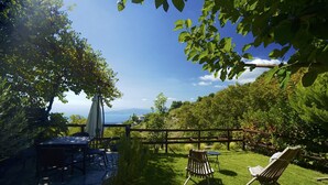 Un patio con tavolo e sedie, una recinzione di legno e un’area verde con due poltrone.