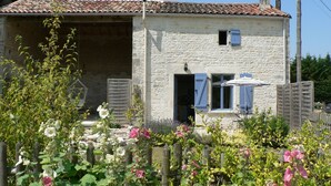 A rustic stone house with a tiled roof, a wooden fence, and blooming flowers in the garden. - Cosy, pet friendly cottage for 2 in pretty countryside (Crézières)