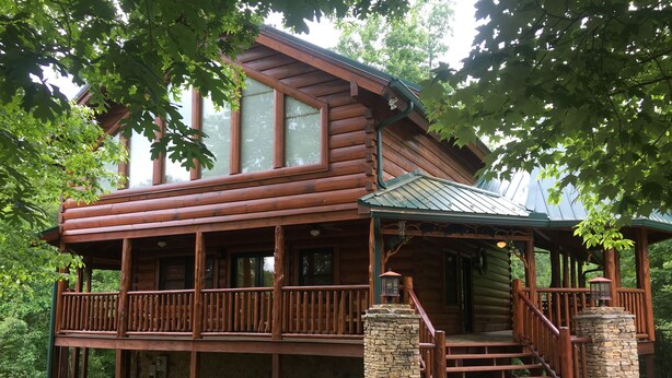 A log cabin with a porch, stone pillars, and a staircase leading to the entrance. - Luxury Cabin, 4 BD/4BA Suites,Half Bath, Game RM, Media RM, Fireplaces, Hot Tub (Sevierville)