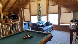 A cozy room with a pool table, a leather sofa, and a Christmas tree. - Luxury Cabin, 4 BD/4BA Suites,Half Bath, Game RM, Media RM, Fireplaces, Hot Tub (Sevierville)