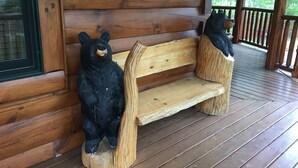 A wooden bench with a bear sculpture on it, located on a wooden porch with a railing. - Luxury Cabin, 4 BD/4BA Suites,Half Bath, Game RM, Media RM, Fireplaces, Hot Tub (Sevierville)