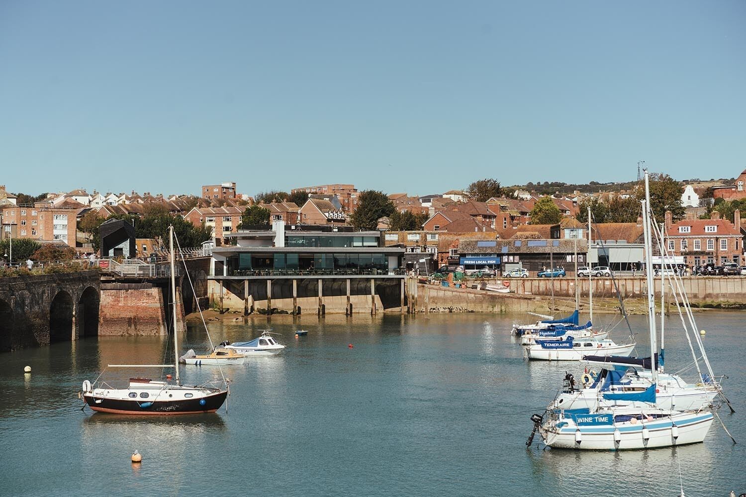 A harbor with boats, a bridge, and buildings in the background.