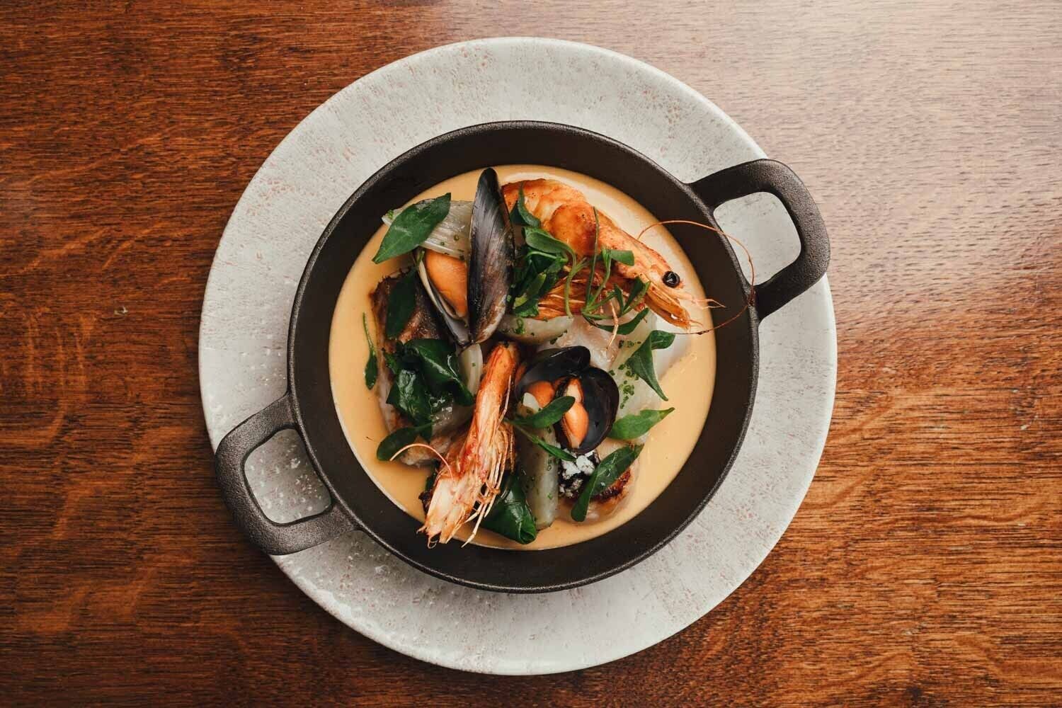 Un plato de mariscos en una sartén de hierro fundido sobre un plato blanco.