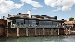 A modern waterfront building with a glass facade, outdoor seating area, and a view of the water. - Rocksalt (Folkestone)