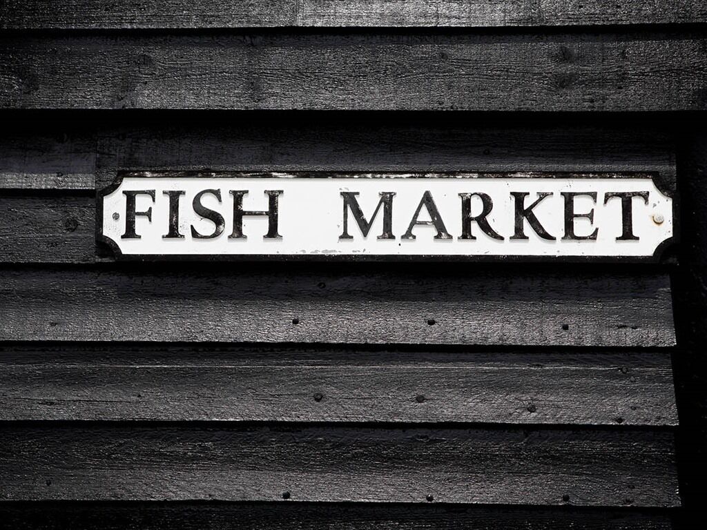 A sign that reads "FISH MARKET" on a wooden background.