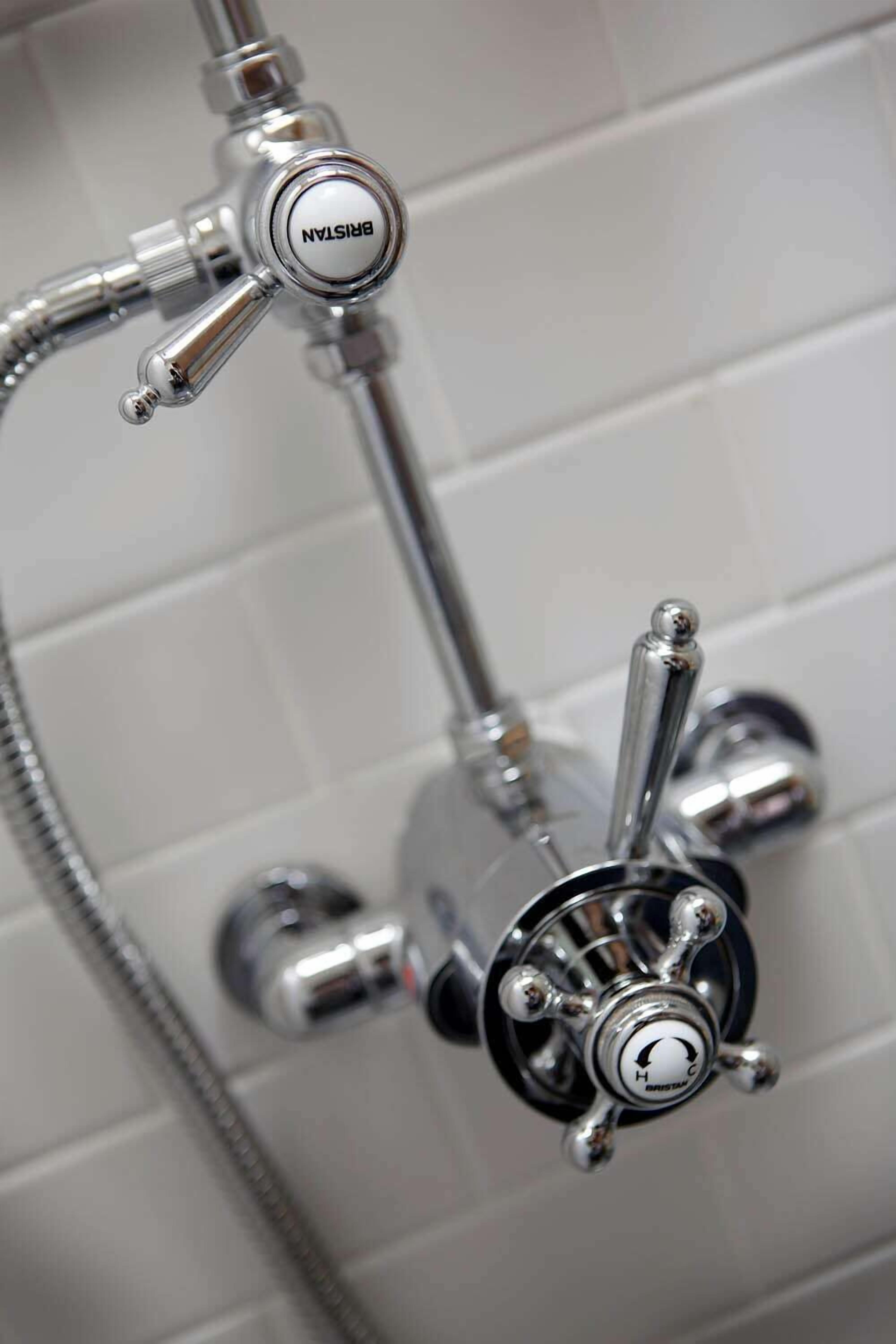 A bathroom with a modern shower system, including a handheld showerhead and a wall-mounted faucet.