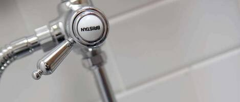 A bathroom with a modern shower system, including a handheld showerhead and a wall-mounted faucet.