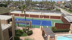 Un court de tennis avec une piscine et des palmiers.
