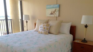 Une chambre à coucher comprenant un lit, deux tables de chevet, une commode, une fenêtre donnant sur un beau paysage et un tableau accroché au mur.