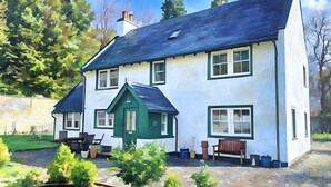 A two-story house with a green door, multiple windows, and a small porch with seating. - Braemore Walled Garden B&B (Garve)