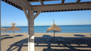 A beach with thatched umbrellas and a clear view of the sea.