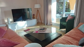 A living room with a flat-screen TV, a lamp, a coffee table, and a sofa.