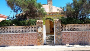 A gated entrance with a stone wall and a decorative metal gate.