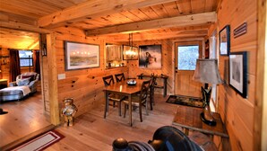 Interior de una cabaña de madera con comedor, chimenea y una sala de estar acogedora.