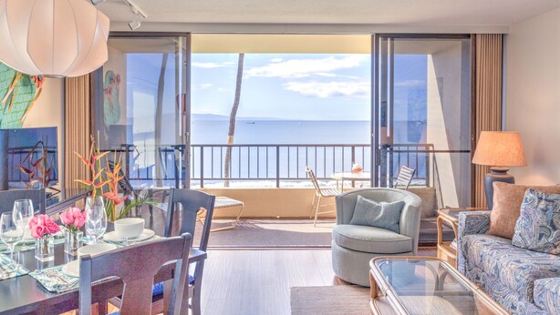 Une chambre d’hôtel moderne dotée d’un balcon, d’un coin repas et d’un espace salon avec vue sur la mer.