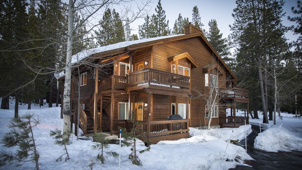 Eine große Holzhütte mit mehreren Balkonen, umgeben von Schnee und Bäumen.