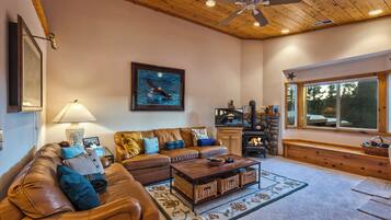A cozy living room with a fireplace, leather sofas, a coffee table, and a large window.