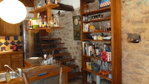 A rustic kitchen with wooden shelves, a dining table, and a clock on the wall. - "La Bouyerie" cottage in a lovely setting, open countryside, breathtaking view (Najac)