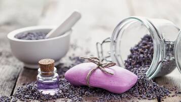 Una superficie de madera con un tarro de vidrio, un mortero y una pequeña botella de aceite de lavanda.