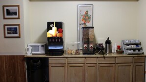 Een keuken met een koffieapparaat, een magnetron en een automaat voor fruit.
