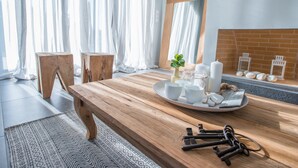 A wooden dining table with a tray of white cups and candles, a small plant, and keys.