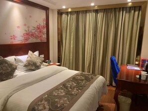 A hotel room with a bed, a desk, a chair, a trash bin, and a curtain. - Greentree Alliance Guangdong Shenzhen Foyong Subw (SHENZHEN)