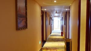 A hotel hallway with a carpet featuring a floral pattern, wooden paneling on the walls, and a framed picture on the left. - Greentree Alliance Guangdong Shenzhen Foyong Subw (SHENZHEN)