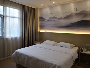 A hotel room with a large bed, a nightstand with a phone, and a wall mural of mountains. - Greentree Inn Ningbo Dongqian Lake Yinxian Mozhi (Ningbo)