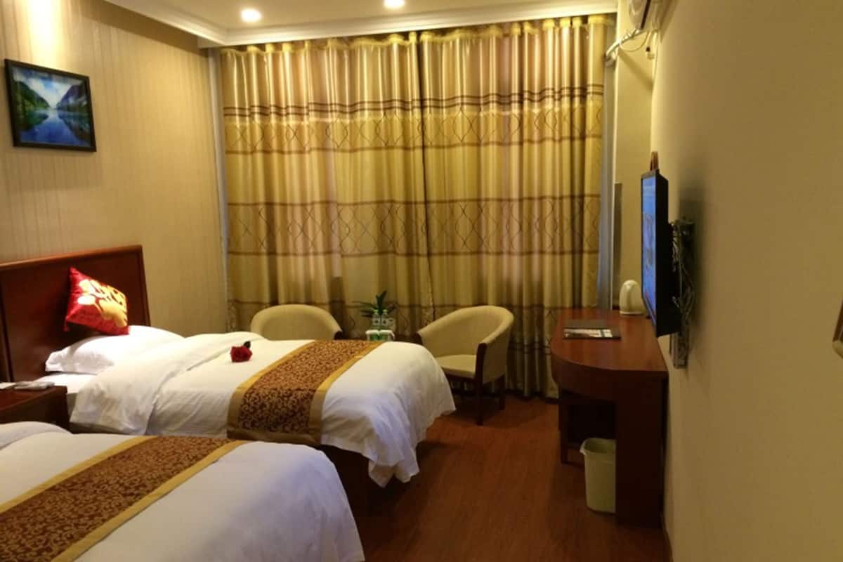 Ein Hotelzimmer mit zwei Betten, einem Schreibtisch, einem Stuhl, einem Fernseher und einem Bild an der Wand.