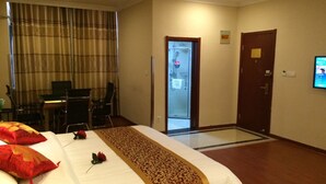 Ein Hotelzimmer mit einem Bett, einem Schreibtisch und einem Sessel. Eine Tür führt ins Badezimmer.