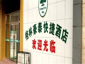 A hotel sign with Chinese characters and a logo for Green Tree Inn.