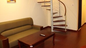 A living room with a curved staircase, a sofa, and a coffee table. - GreenTree Inn TianJin JinNan ShuangLin Metro Station Express Hotel (Tianjin)