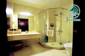 A bathroom with a glass-enclosed shower, a sink with toiletries, and a toilet.