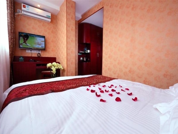 A hotel room with a bed, a TV, a desk, and a wardrobe.