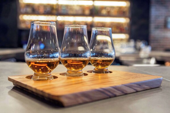 Tres vasos de líquido ámbar sobre un posavasos de madera.