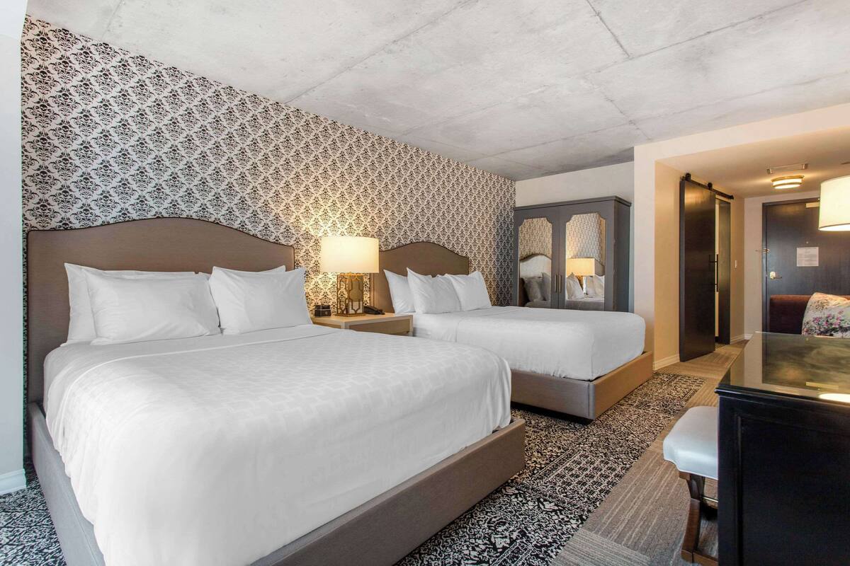 Una habitación de hotel con dos camas, un escritorio y un espejo.