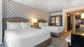 A hotel room with two beds, a desk, and a mirror.