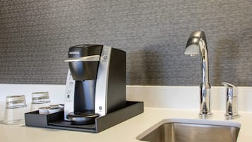 A modern kitchen with a Keurig coffee maker, a stainless steel sink, and a sleek faucet.