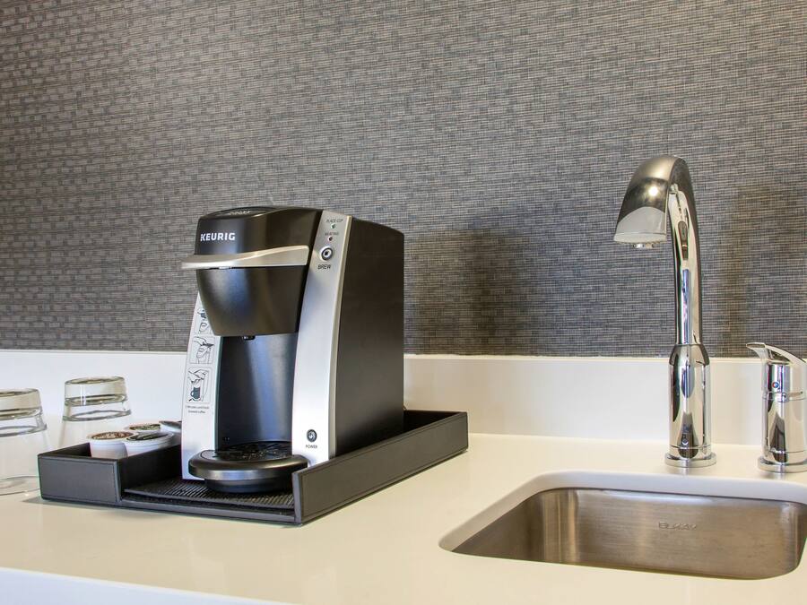 A modern kitchen with a Keurig coffee maker, a stainless steel sink, and a sleek faucet.