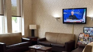 A living room with a television mounted on the wall, a sofa, a coffee table, and a lamp.