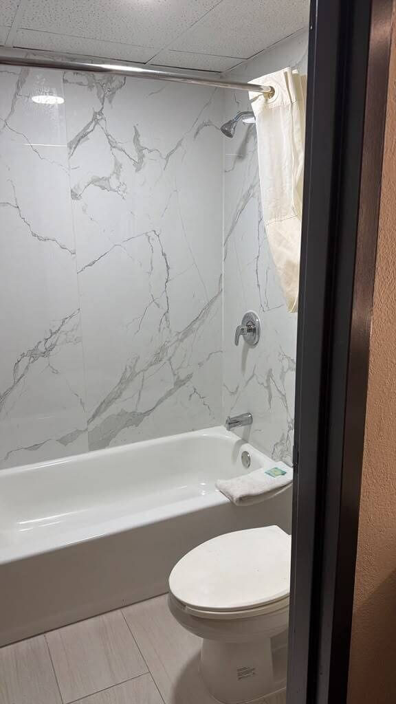 Une salle de bain avec une baignoire, des toilettes et des murs en marbre.