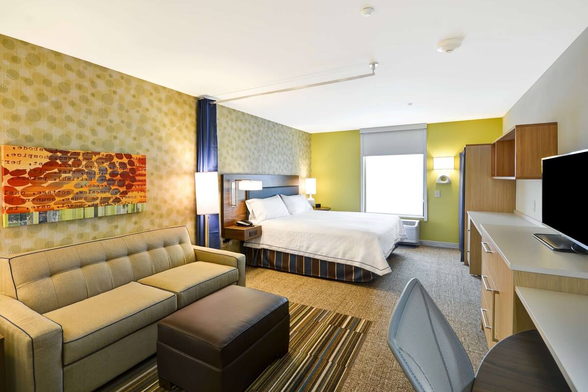 Une chambre d’hôtel avec un lit, un canapé, un bureau et une télévision.