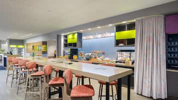 Un ristorante moderno con un lungo bancone, sedie arancioni e un cartello con la scritta 'inspired table'.