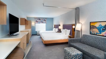 Une chambre d’hôtel avec un lit, un canapé, une télévision, un bureau et un tableau au mur.