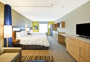 Una habitación de hotel con una cama grande, un escritorio con televisor de pantalla plana, un sofá y un baño con ducha e inodoro.