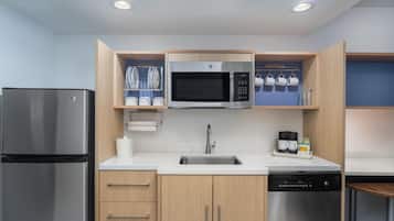A modern kitchen with a stainless steel refrigerator, a microwave, a dishwasher, and wooden cabinets.