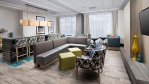 Een moderne hotelkamer met een hoekbank, een bar, een eettafel en een flatscreen televisie.